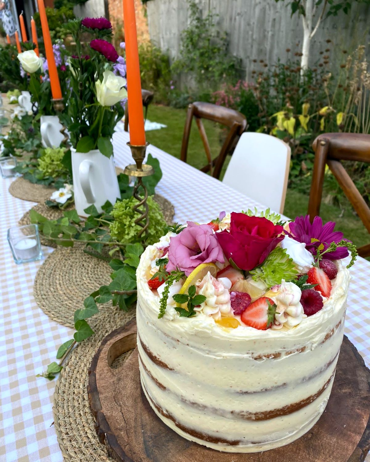 Semi-naked cake with roses and strawberries on a garden party table